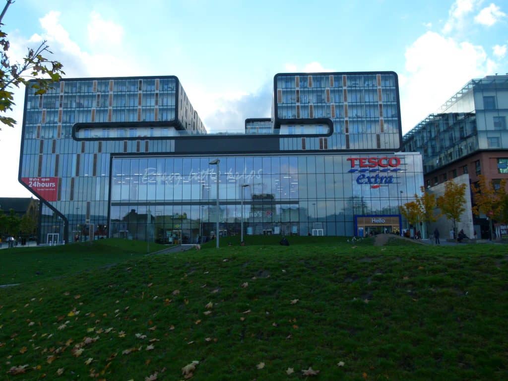 A glass-faced Tesco building on top of a grassy hill