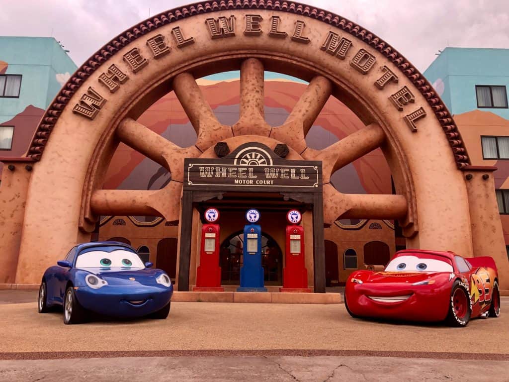 Art of Animation Cars theming with two cars outside the entrance with a big "Wheel Well Motel" sign and gas pumps around them