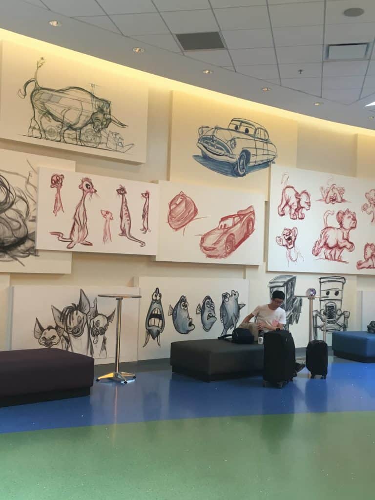 A man sitting on a chair in front of hand-drawn artwork at Disney's Art of Animation resort