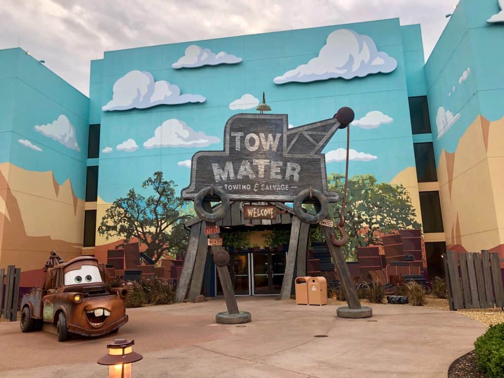 Entrance to building at Disney's Art of Animation Resort with a Cars character in front and a sign saying "Tow Mater Towing and Salvage"
