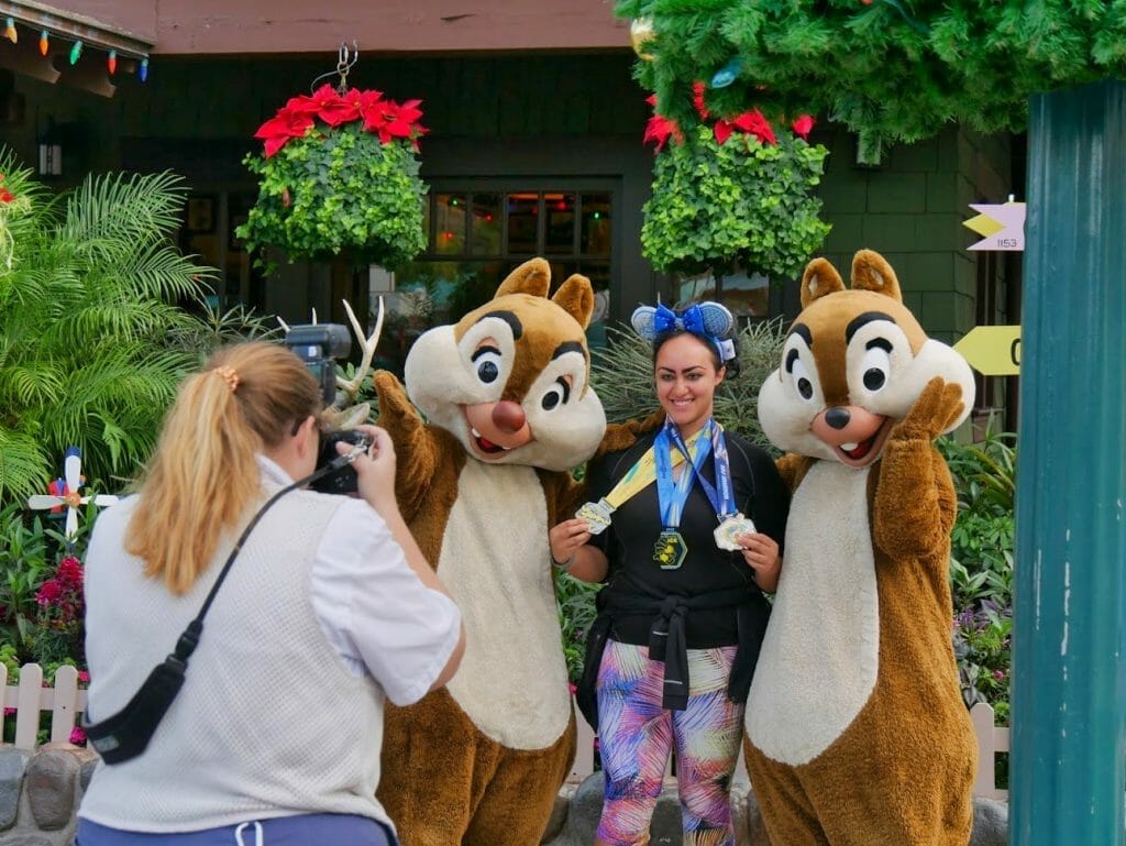 Chip and Dale taking a photo with a guest with Christmas decorations behind them at Hollywood Studios at Christmas