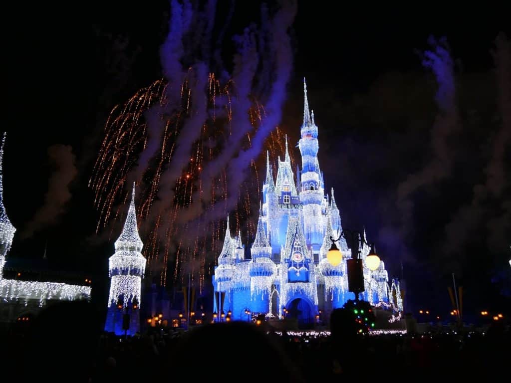 Fireworks over the castle lit up in white lights at the Magic Kingdom in Disney World at Christmas