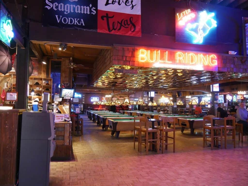 Inside of Billy Bob's in Fort Worth, with pool tables and a big neon sign that says "Bull Riding"