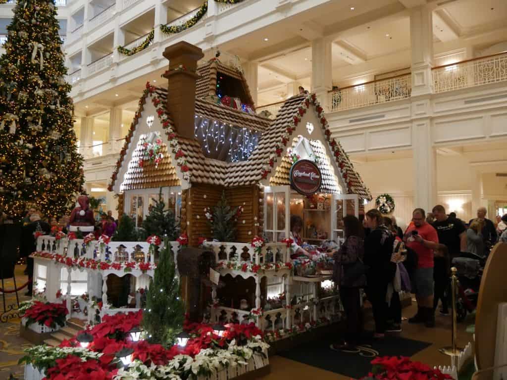 A Disney gingerbread house with people shopping at the Grand Floridian Disney World resort at Christmas