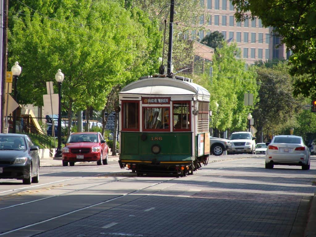 A trolley traveling down a road with cars either side in Texas