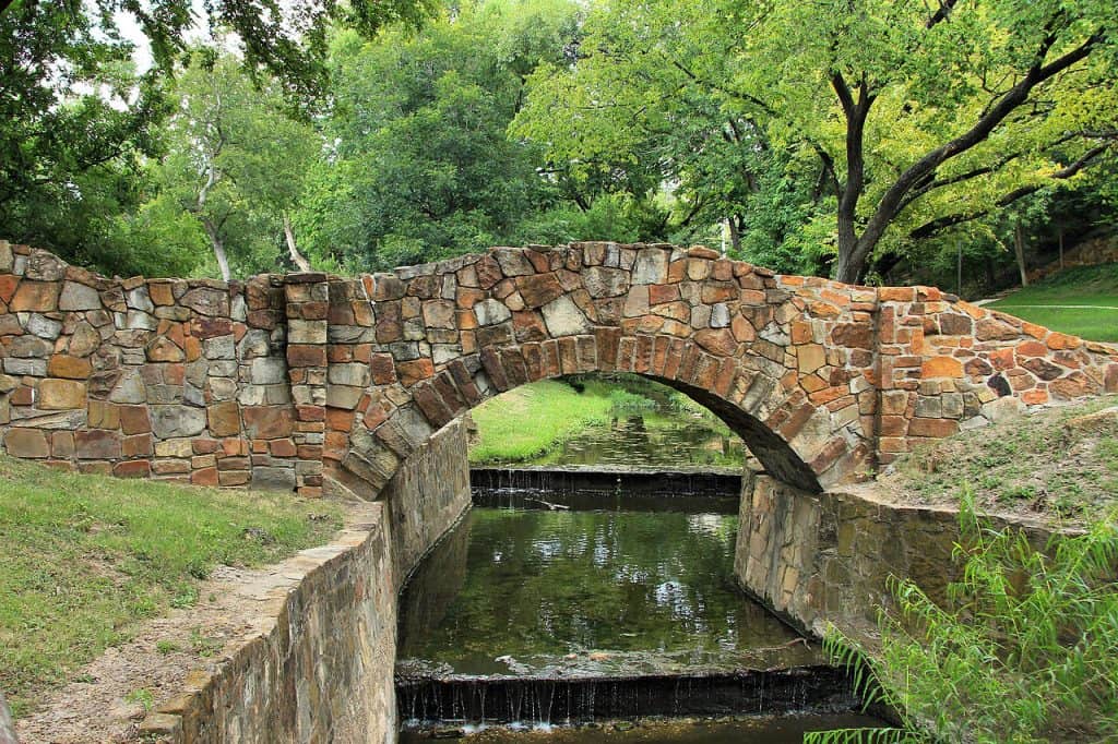 A stone bridge going over a stream in Reverchon Park in Dallas