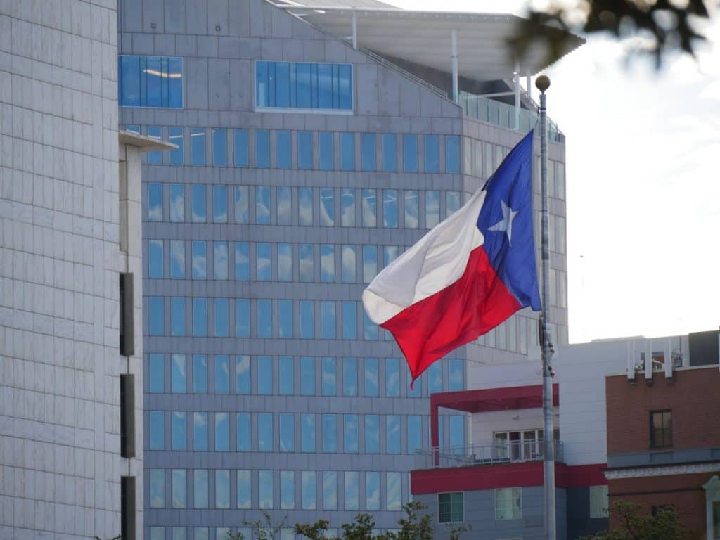Texas flag with glass building behind taken in Dallas
