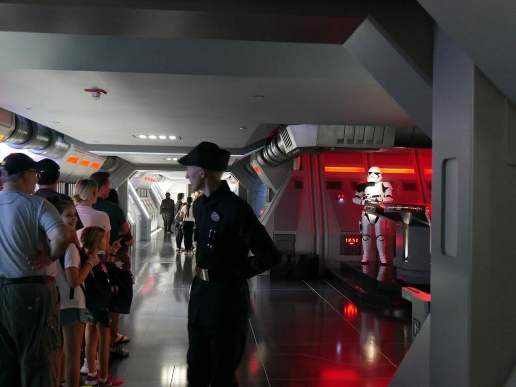 An Imperial soldier with Stormtroopers behind and people queueing