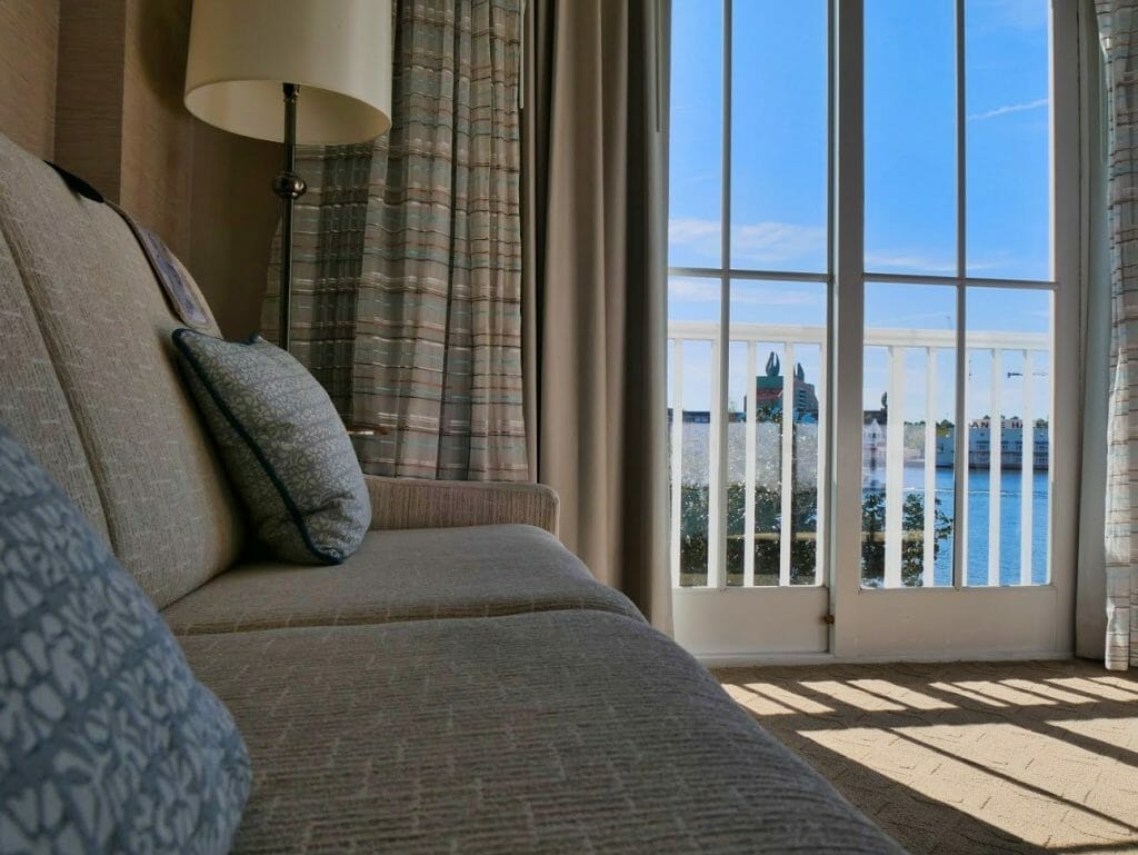 A nice couch with a view out of a balcony over water in an upgraded room at Beach Club resort