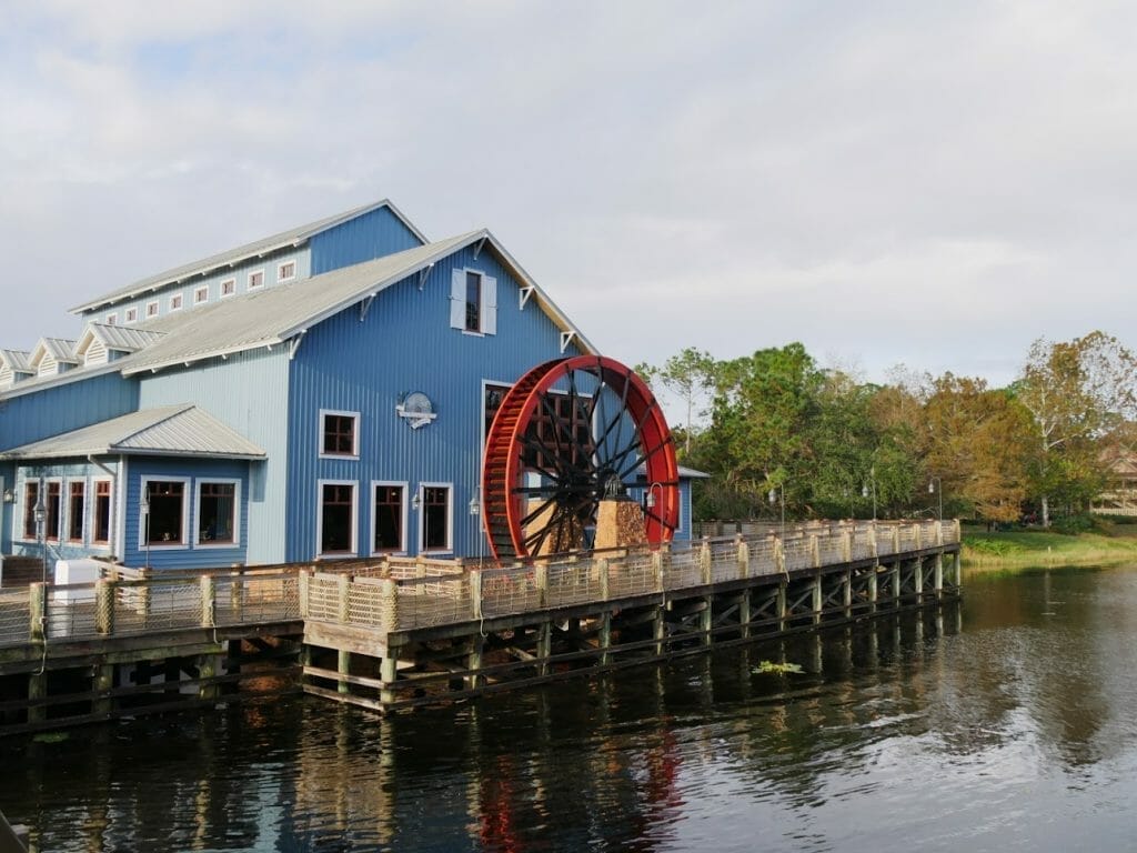 A blue wooden building with a red water wheel