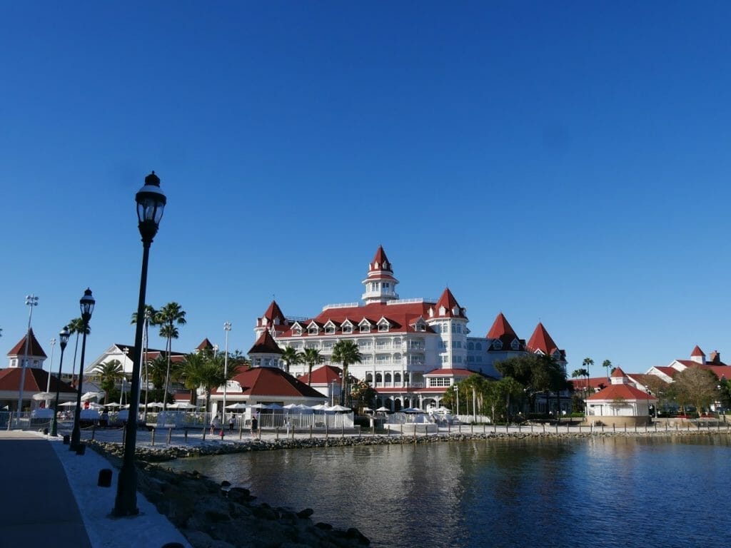 The Grand Floridian Resort Disney World with a lake in front on a blue sky day