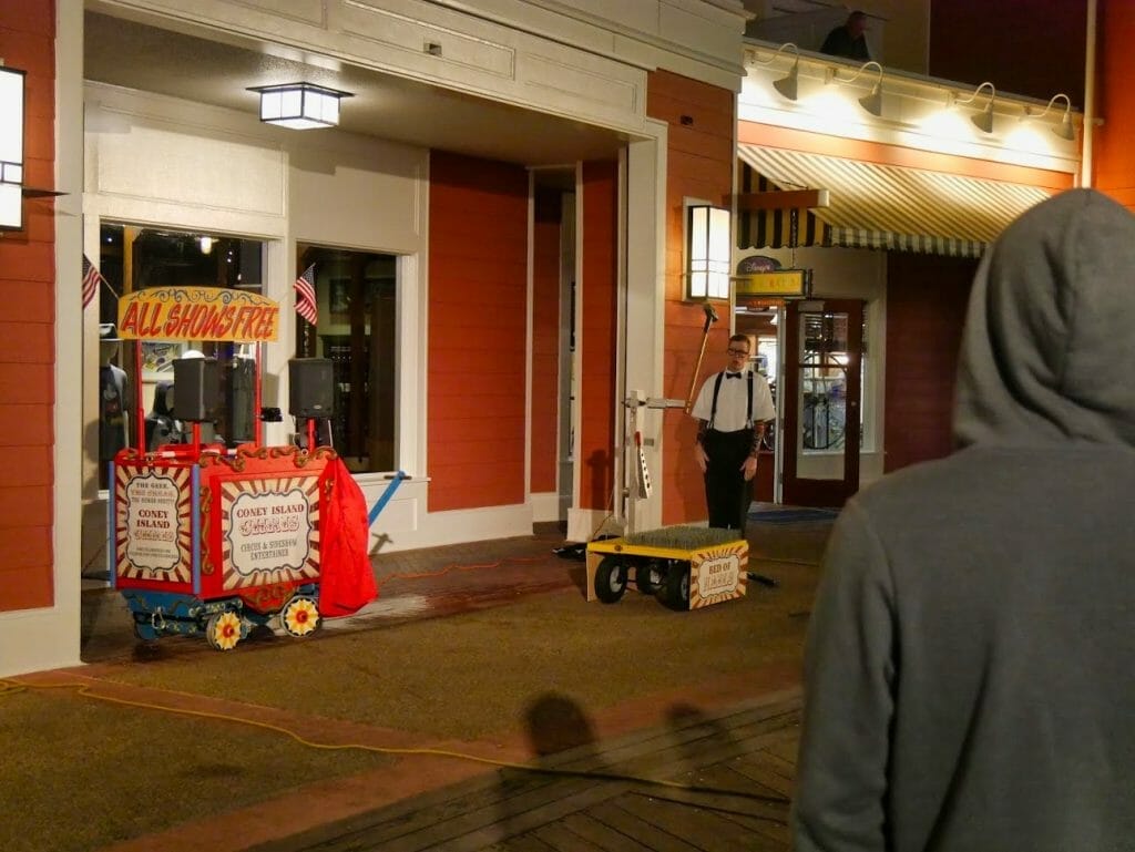 A free comedy show at the Disney Boardwalk with a man with spikes on a table and a large hammer