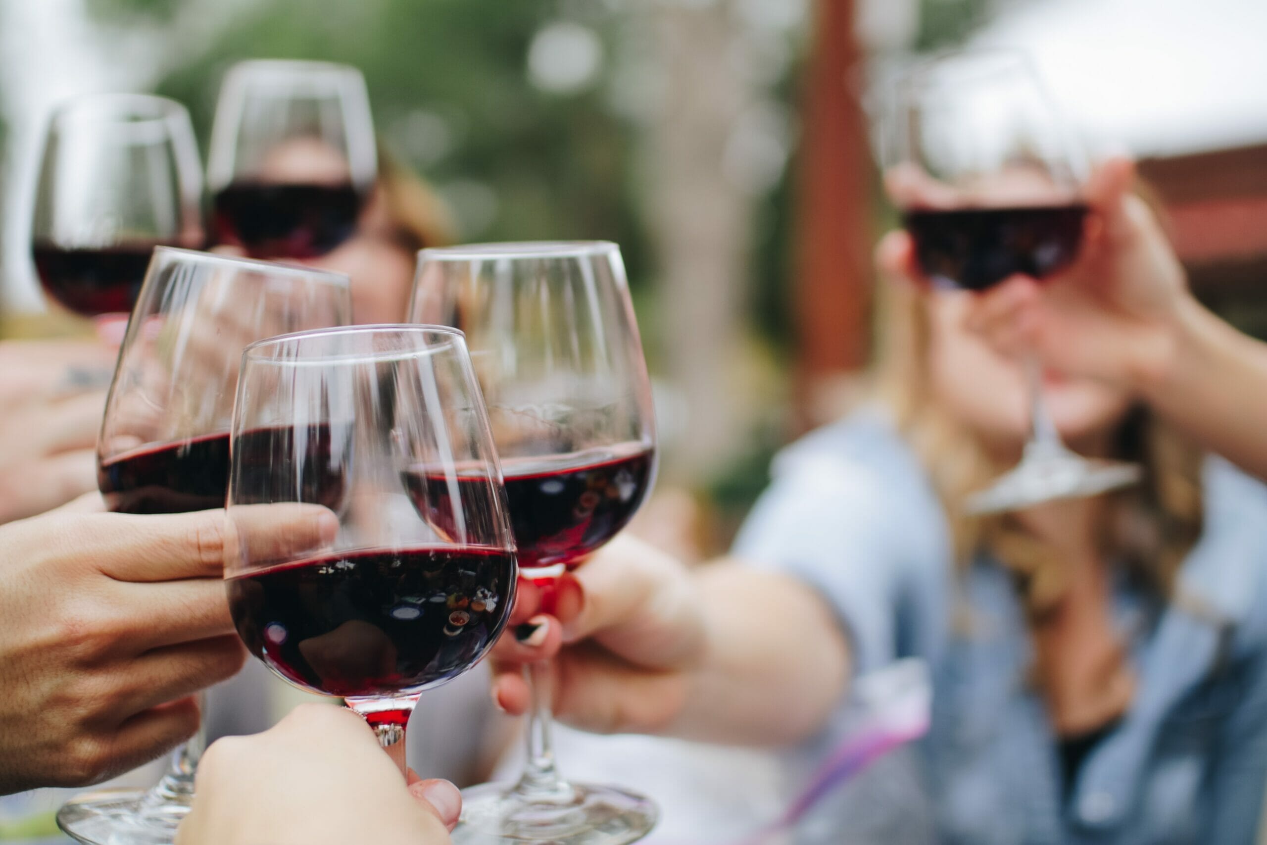 People toasting wine glasses with red wine