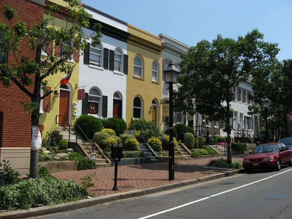 Colorful townhomes along a brick-sidewalked street in Alexandria, Virginia