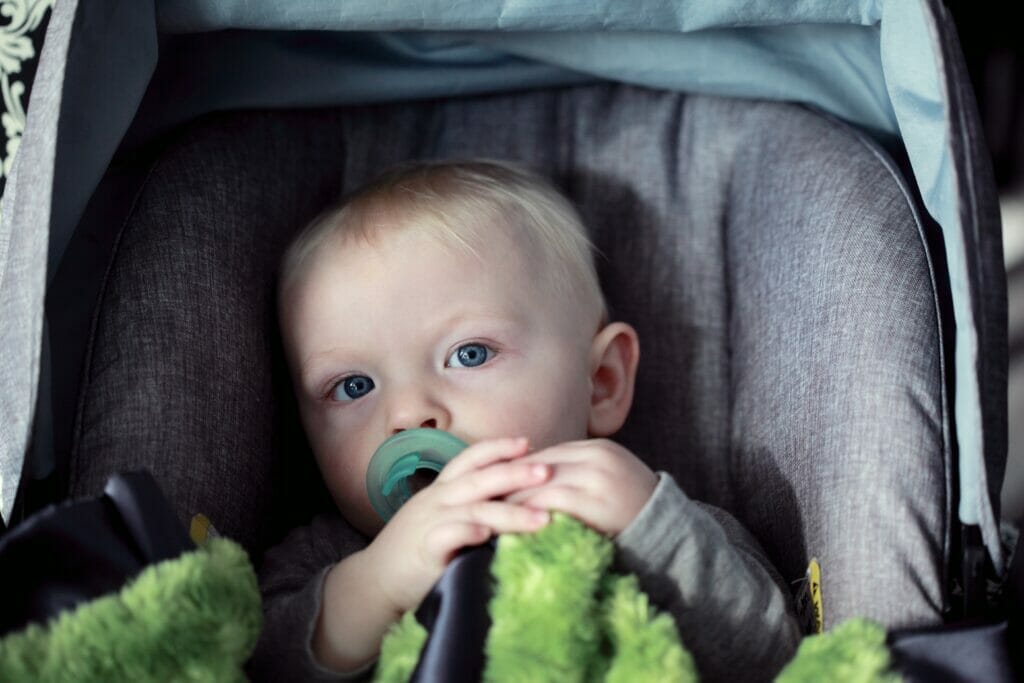 A baby with a pacifier sitting in a car seat
