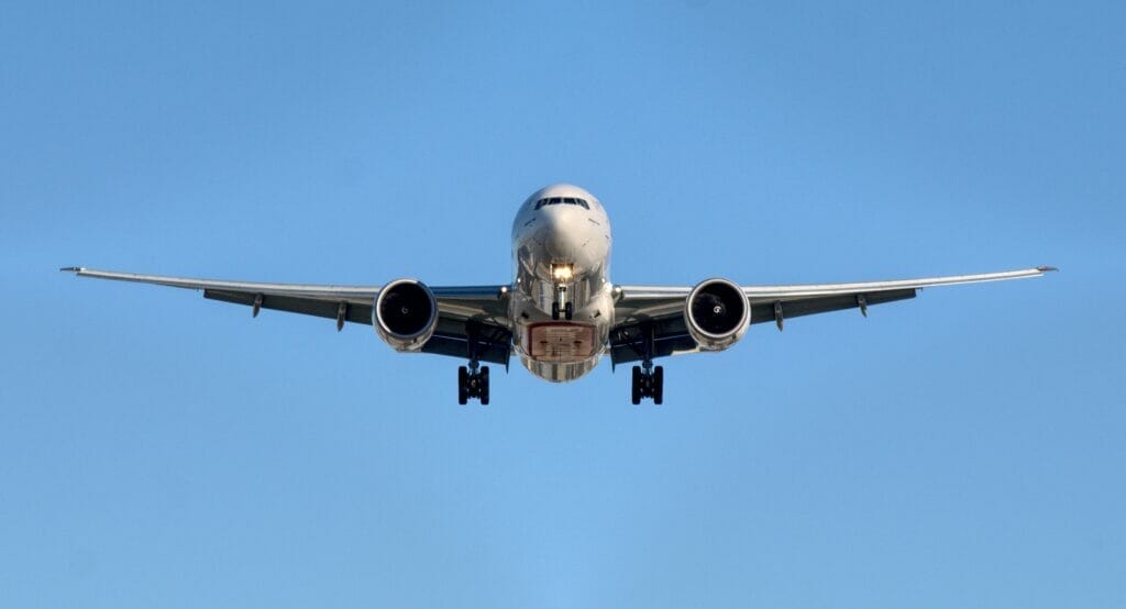 Front of an airplane amidst a blue sky