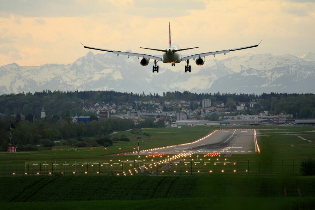 A plane landing at an airport with mountains in the background
