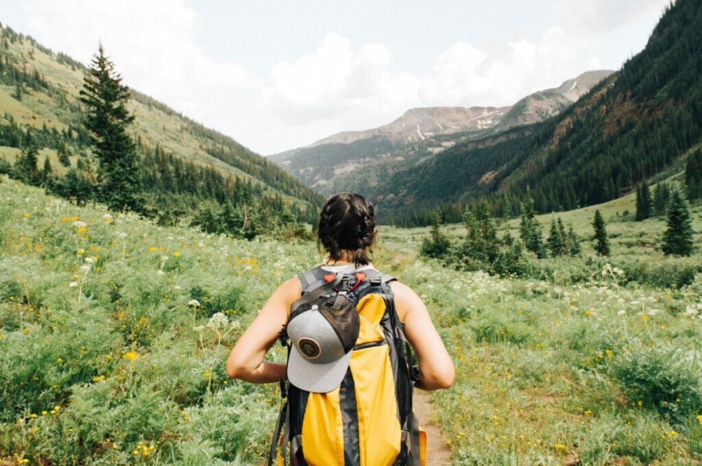 girl with backpack looking out into the mountains