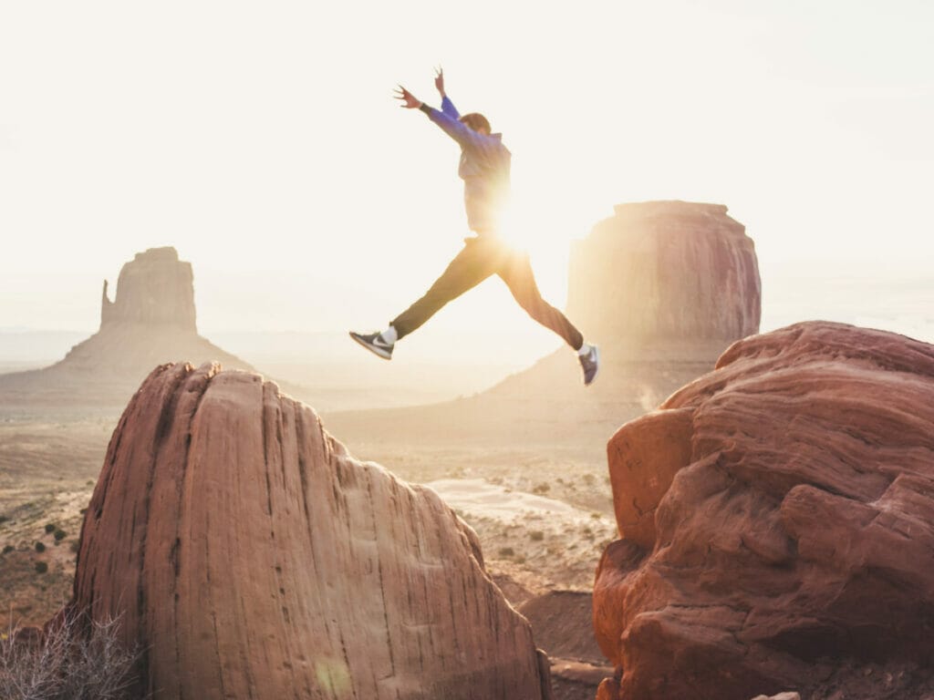 person jumping over two rocks