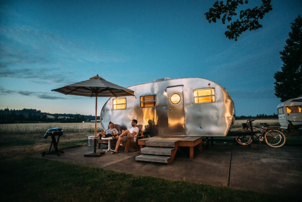 camper rv with two people sitting in front of it