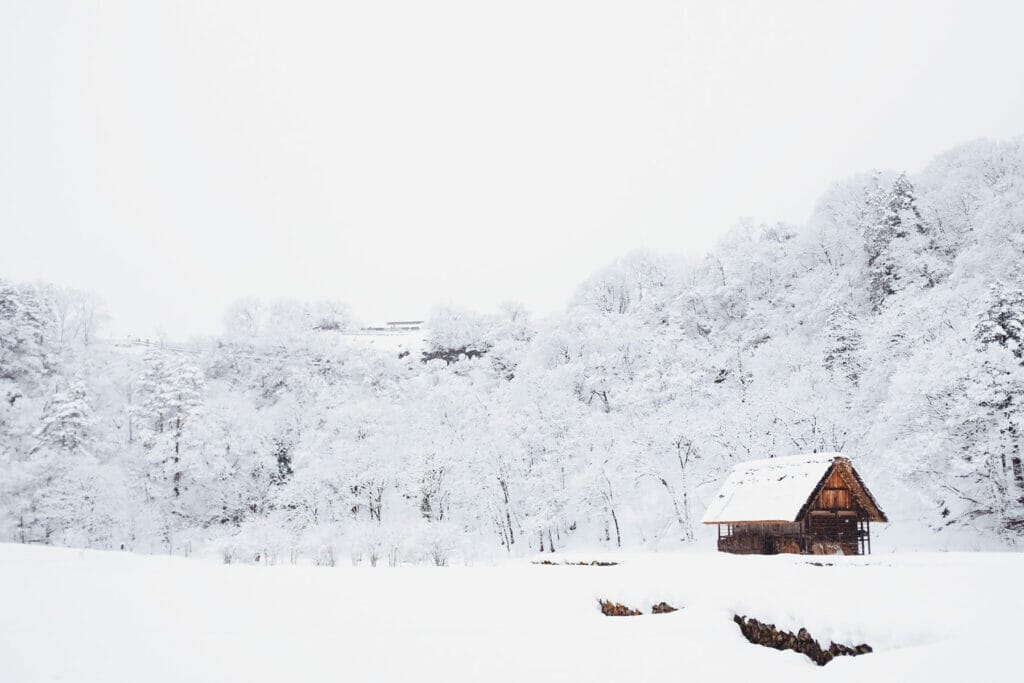 snow covered landscape with small cabin