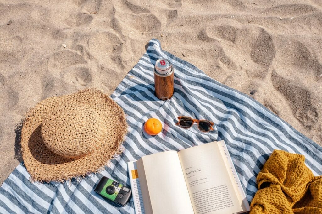 hat blanket and book on the sand