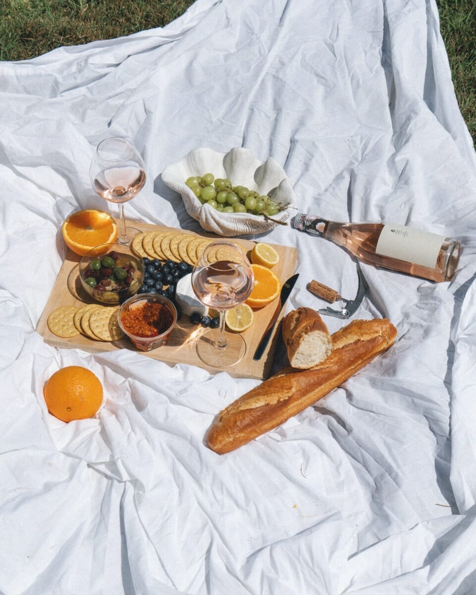 A luxurious picnic assortment spread out on a white blanket in the park