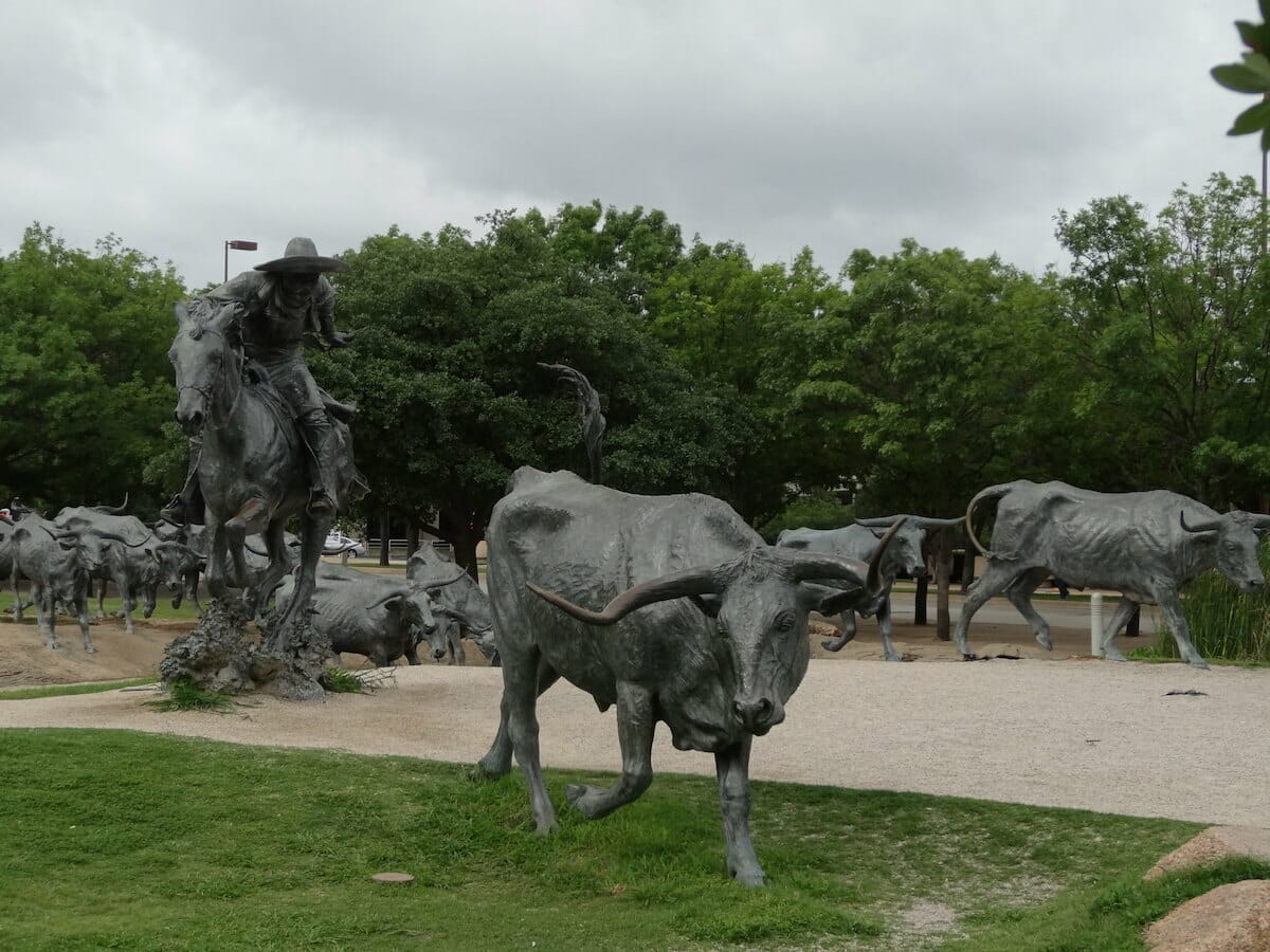 Sculptures of a cattle driver on a horse herding cattle at Pioneer Plaza in Dallas