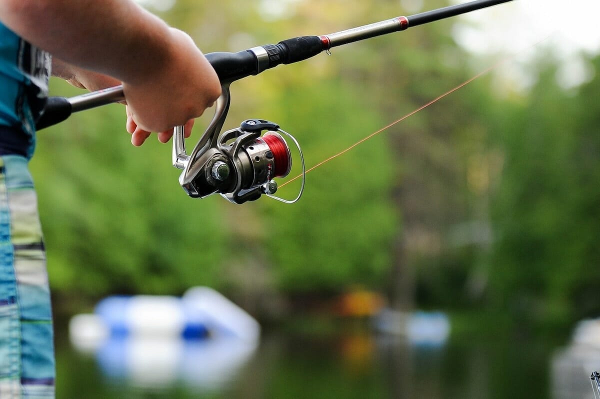 Close-up of a person holding a fishing rod over a lake