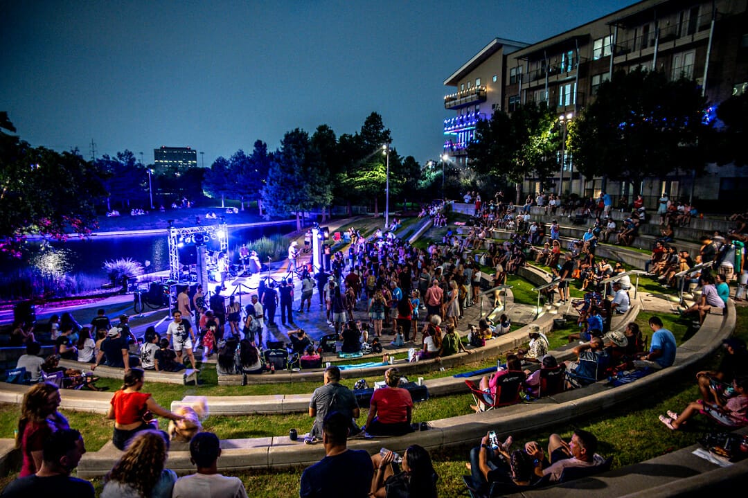A crowd gathers in front of the amphitheater in Vitruvian Park for a concert in Addison Texas