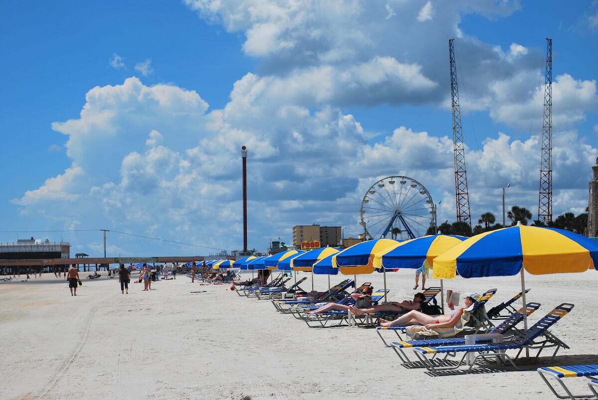 White sands and people relaxing under blue and yellow umbrellas at Daytona Beach