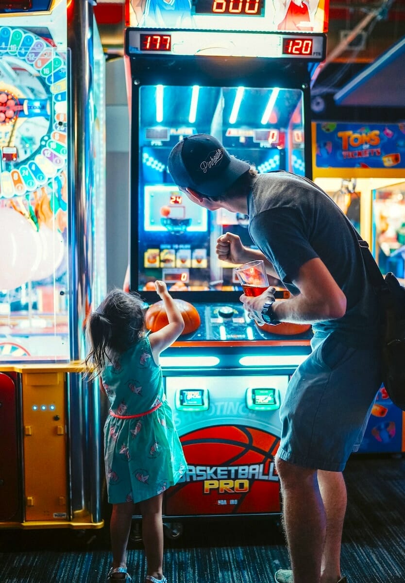An adult and a child playing a game at an arcade