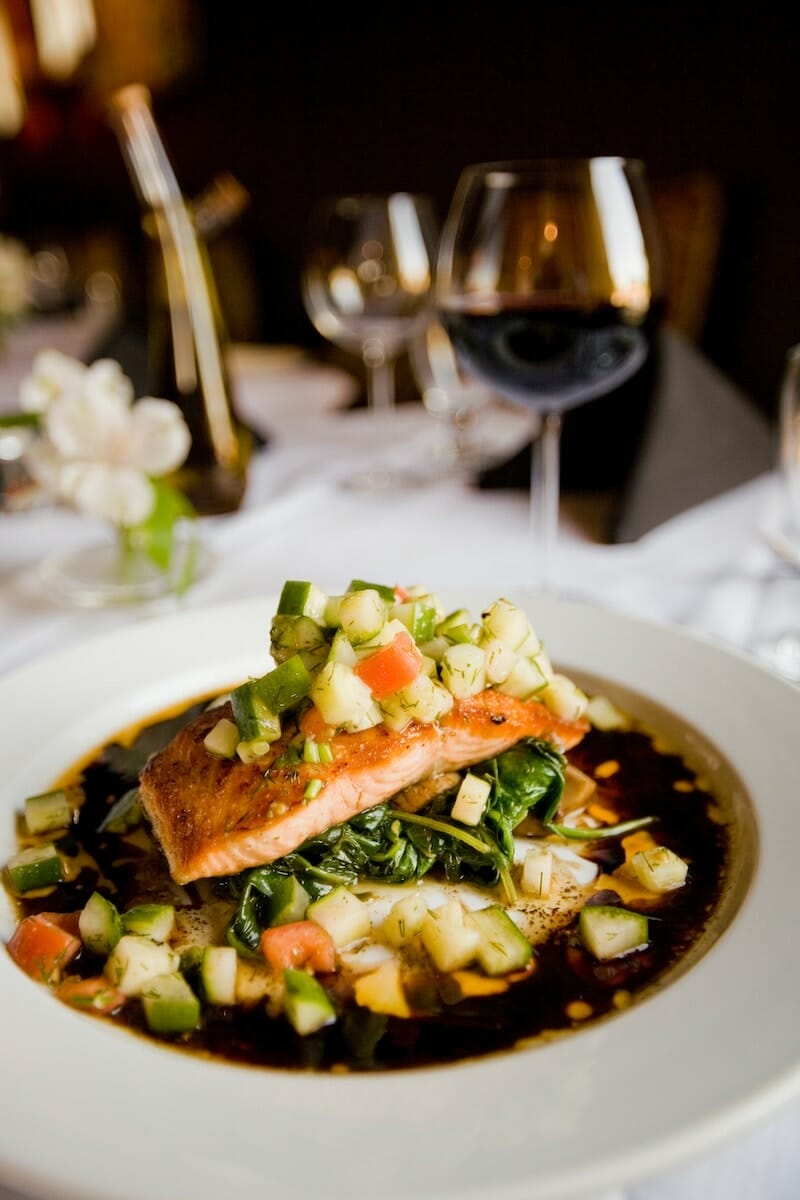 A fine dining salmon dish on a white tablecloth