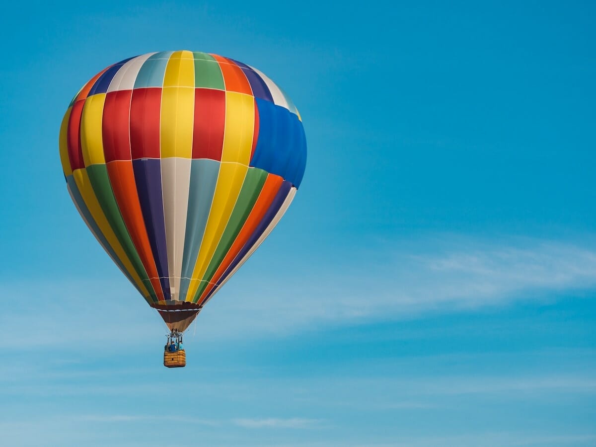 a colorful hot air balloon flying in a clear blue sky