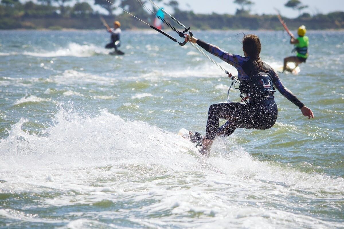 People enjoying water sports like kitesurfing and wakeboarding on a lake