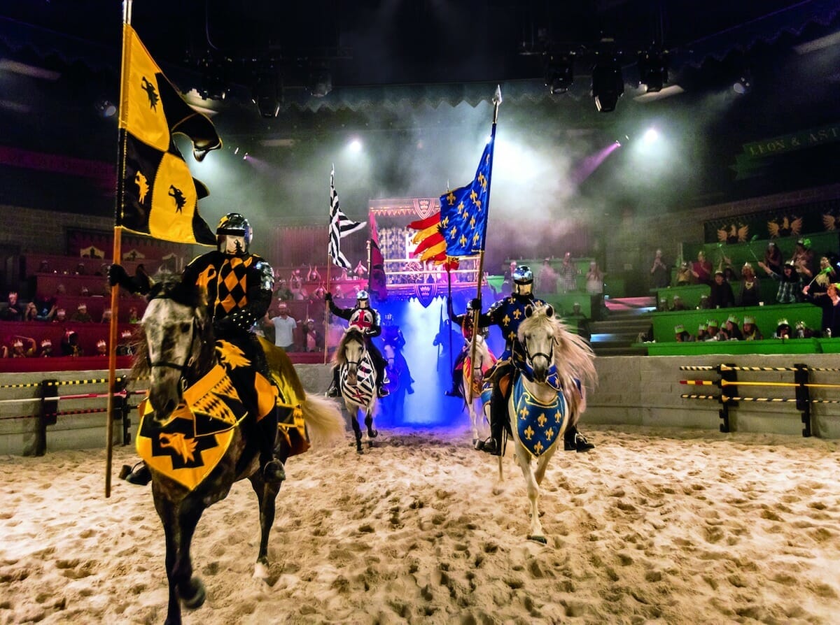 knights ride horses and carry flags at the Medieval Times Dinner & Tournament Orlando