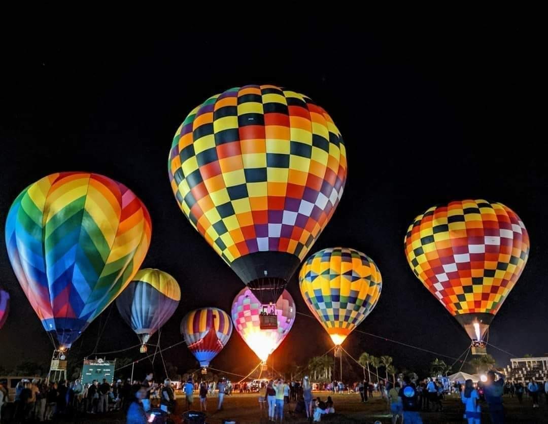 Orlando hot air balloon glow festival, featuring several colorful hot air balloons glowing in a field at night