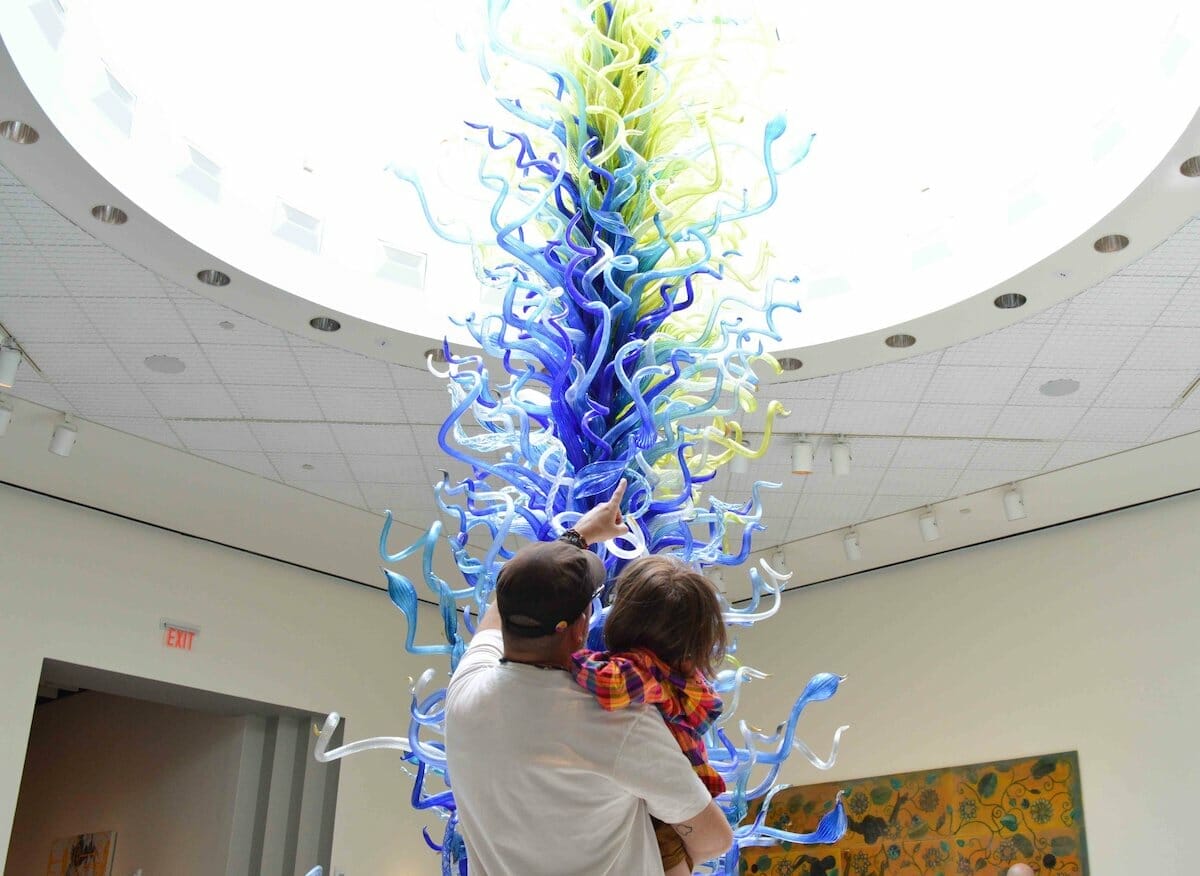 A father and child stand in front of a blue glass sculpture at the Orlando Museum of Art