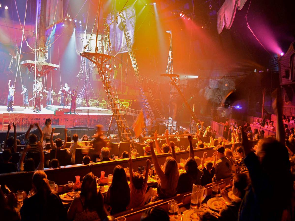 an enthusiastic audience dines and cheers during a show at Pirates Dinner Adventure Orlando