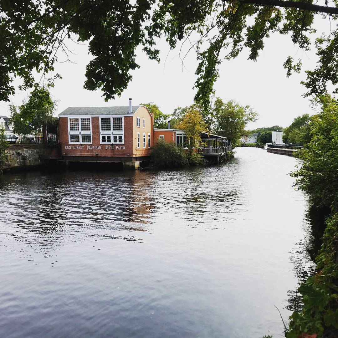 waterfront view of Bridge Restaurant Raw Bar in Westerly Rhode Island, housed in a historic wheelhouse brick building along the Pawcatuck River