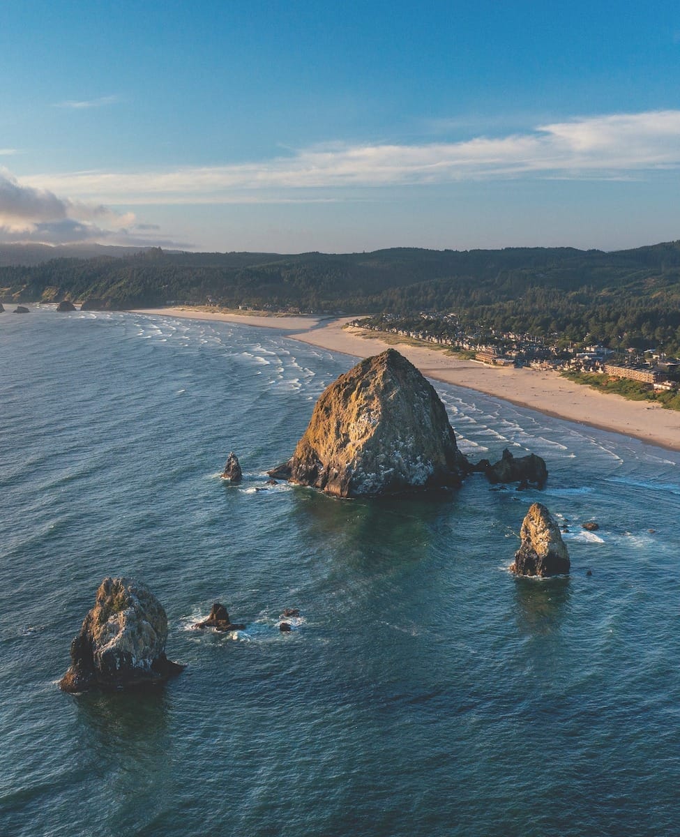 view of Cannon Beach Oregon, one of the most beautiful places in America, featuring a prominent rock emerging from the water near the beach