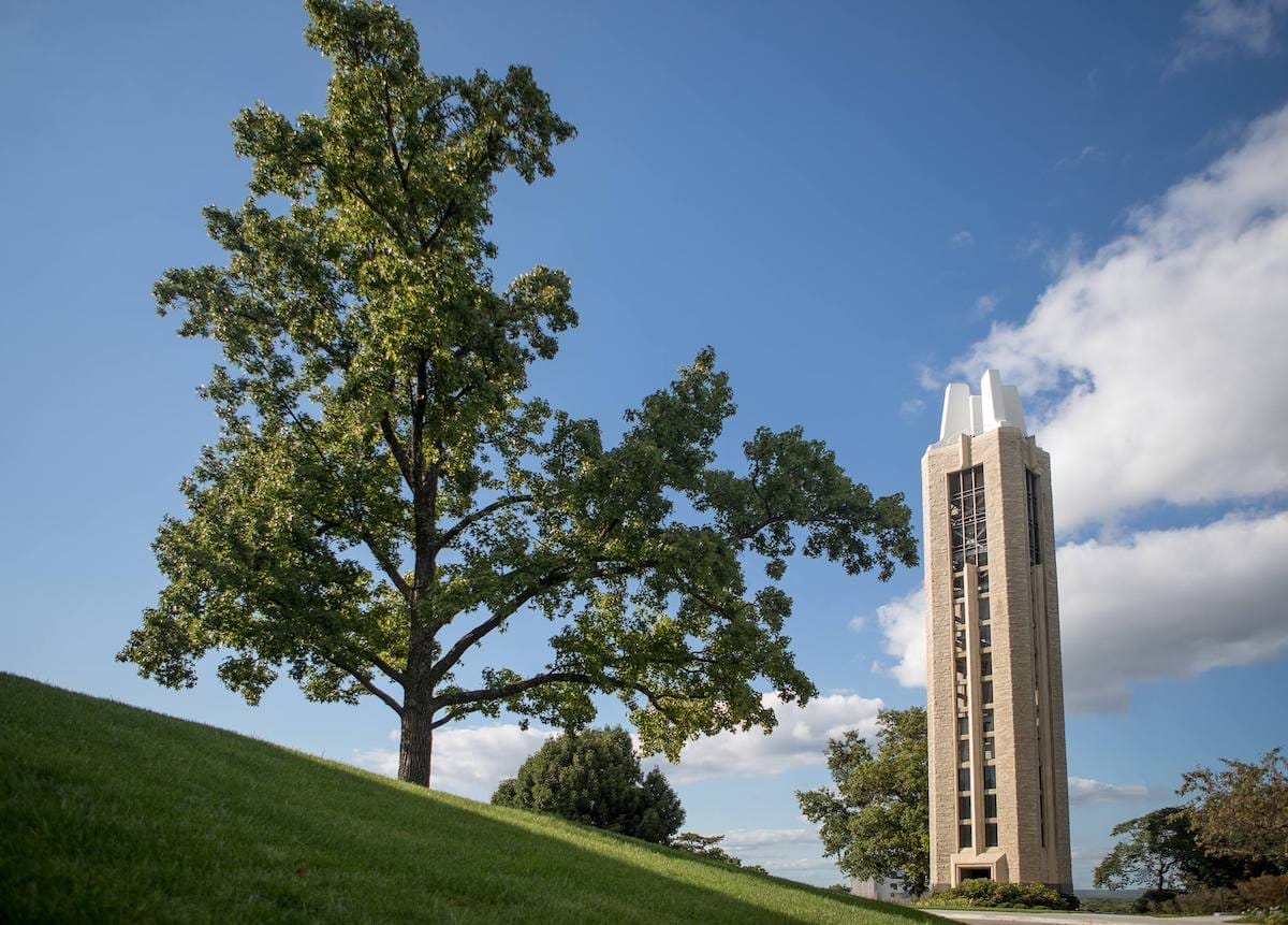 Bell tower on a hill beside a tall tree at the KU campus in Lawrence Kansas