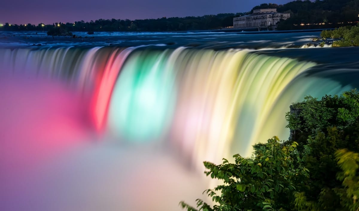 view of Niagara Falls at night, with the water lit up with colorful lights