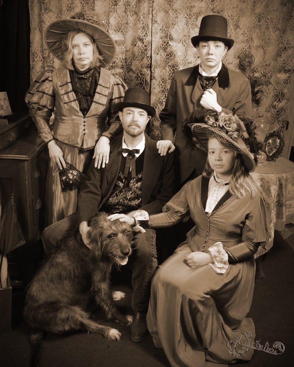 a family and their dog pose in costume with stoic expressions at Emma's Old Time Photos in Cheyenne Wyoming